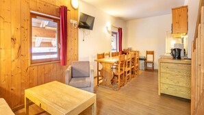 A wooden cabin interior with a dining area, a TV mounted on the wall, and a kitchenette. - Pet-Friendly Family Home with Balcony (Saint-Sorlin-d´Arves)