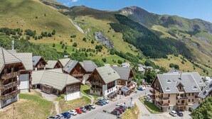 A mountain lodge with multiple wooden buildings, a parking area, and a view of surrounding hills. - Pet-Friendly Family Home with Balcony (Saint-Sorlin-d´Arves)