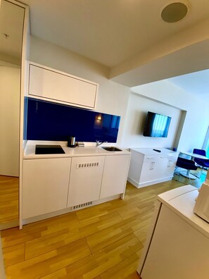A modern kitchen with white cabinetry, a blue backsplash, and a built-in oven. - Modern Sea-View Studio in Orbi City Batumi | Steps from the Beach (Batumi)