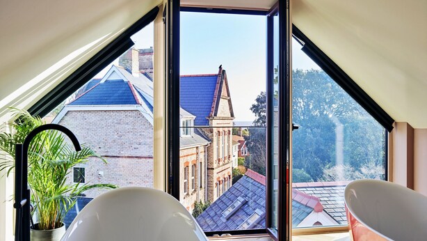 A modern room with a large skylight, a potted plant, and a white bathtub. - Sea Gables (Exmouth)