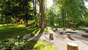 A forested area with a gravel path, wooden posts, and a small structure. - Naturhotel Schloss Kassegg (Sankt Gallen)