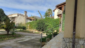 A paved pathway leading to a building with a stone wall and a metal railing. - Laura's Little Houses: Mondello 1 (Palermo)