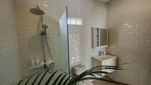 A modern bathroom with white subway tiles, a glass shower enclosure, a white sink, and a mirror above the sink. - Canggu 1 BR Private Pool Villa Polly (Canggu)