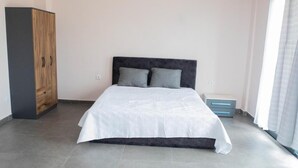 A bedroom with a bed, a wardrobe, and a nightstand. - Nour Apatments (São Tomé)