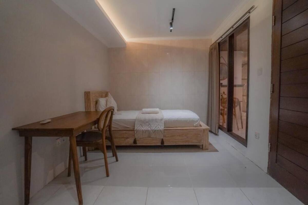 Un dormitorio con una cama de madera, un escritorio pequeño y una silla.