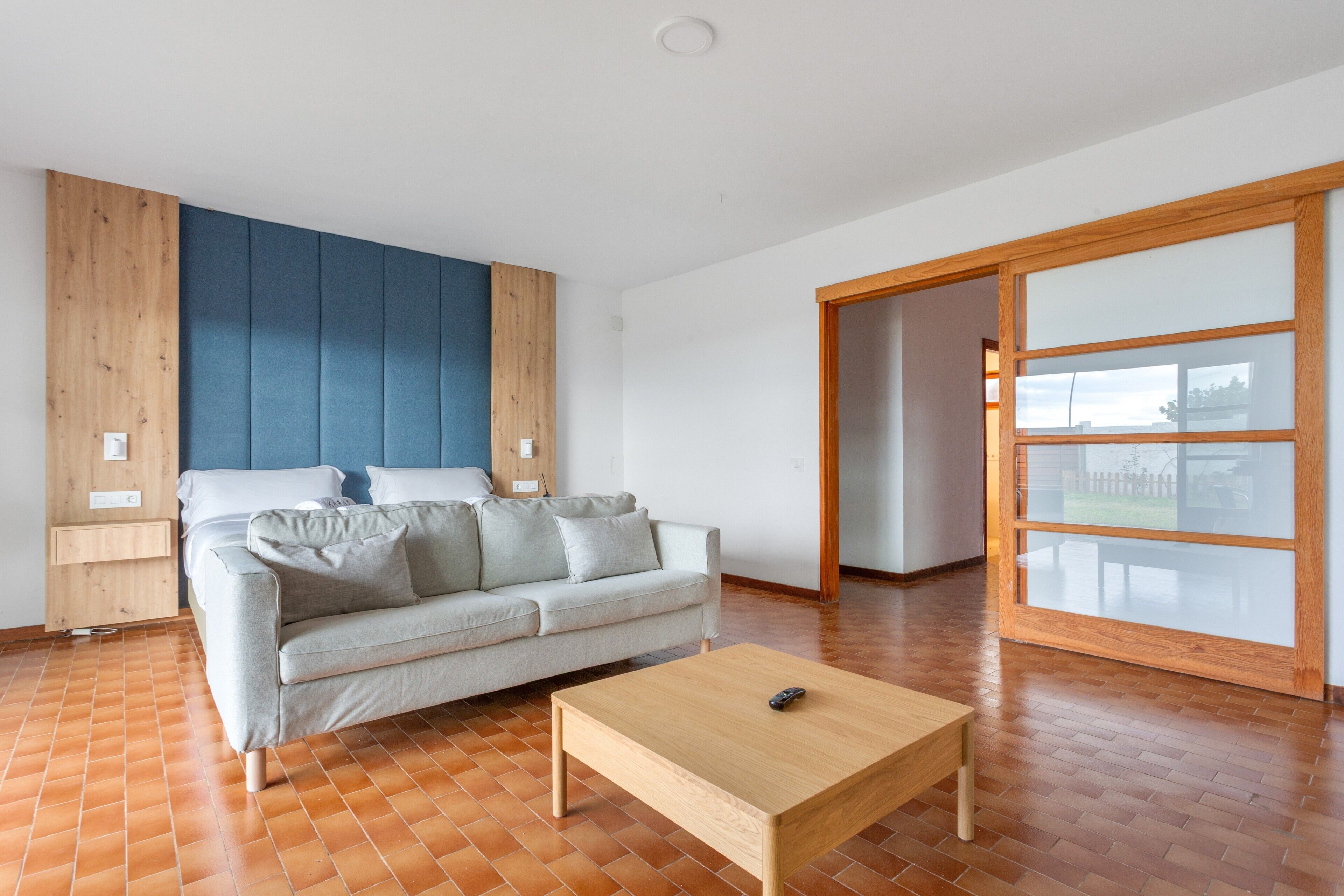 Una sala de estar moderna con un sofá, una mesa de centro y un ventanal corredero que da a un área exterior.