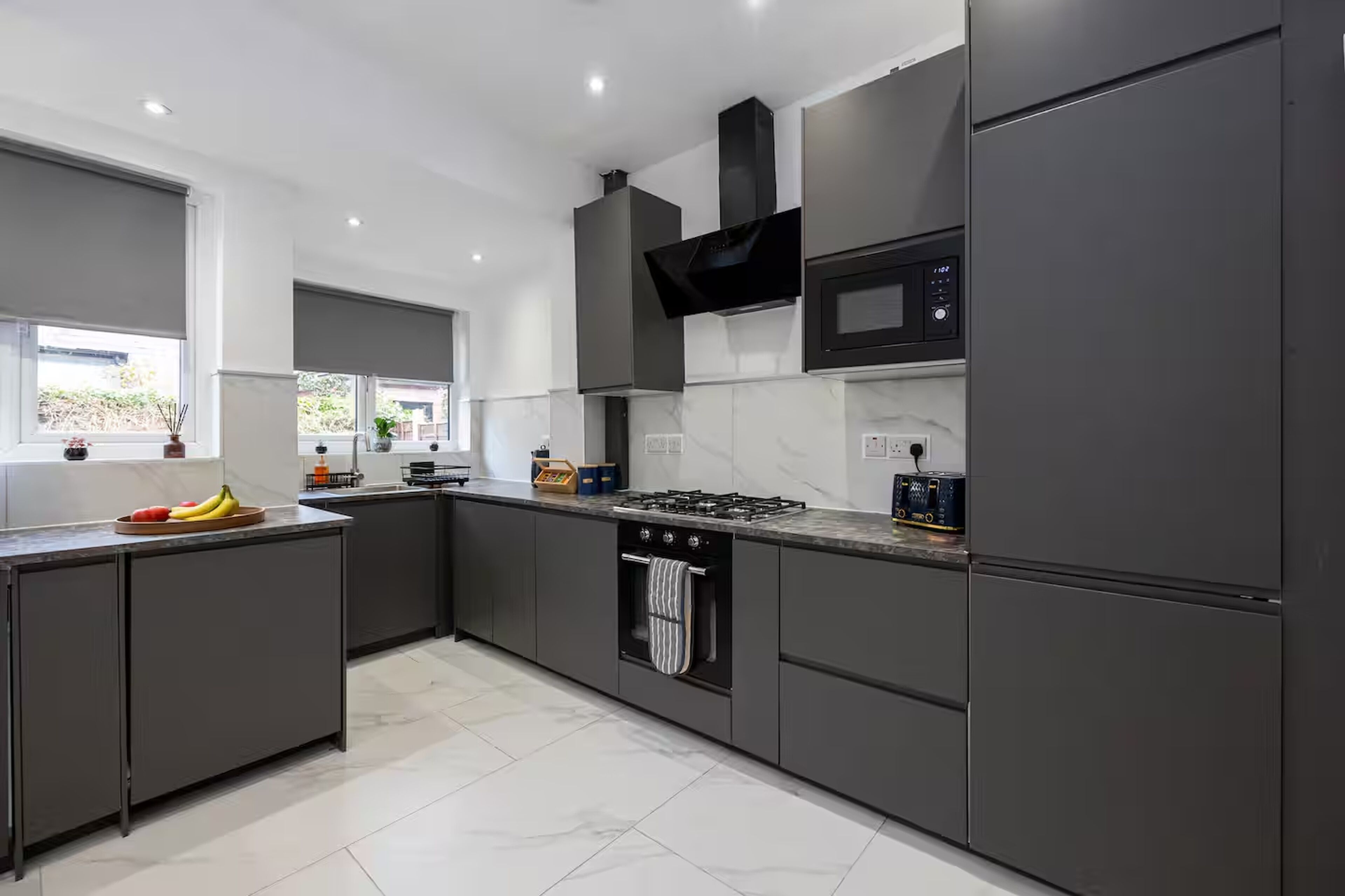 A modern kitchen with dark cabinetry, a gas stove, a microwave, and a built-in oven.