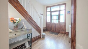A wooden staircase leading to a landing with a vase of flowers, a bench, and a door with a window. - Modern & Spacious 4-Bedroom Home, Family & Contractor Friendly, Manchester (Manchester)