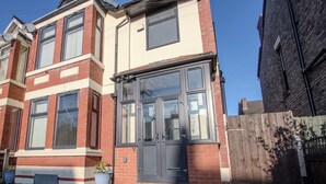 A two-story house with a dark front door, large windows, and a brick facade. - Modern & Spacious 4-Bedroom Home, Family & Contractor Friendly, Manchester (Manchester)