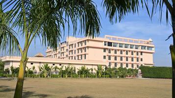 A multi-story building with a flat roof, surrounded by a well-maintained lawn and palm trees.