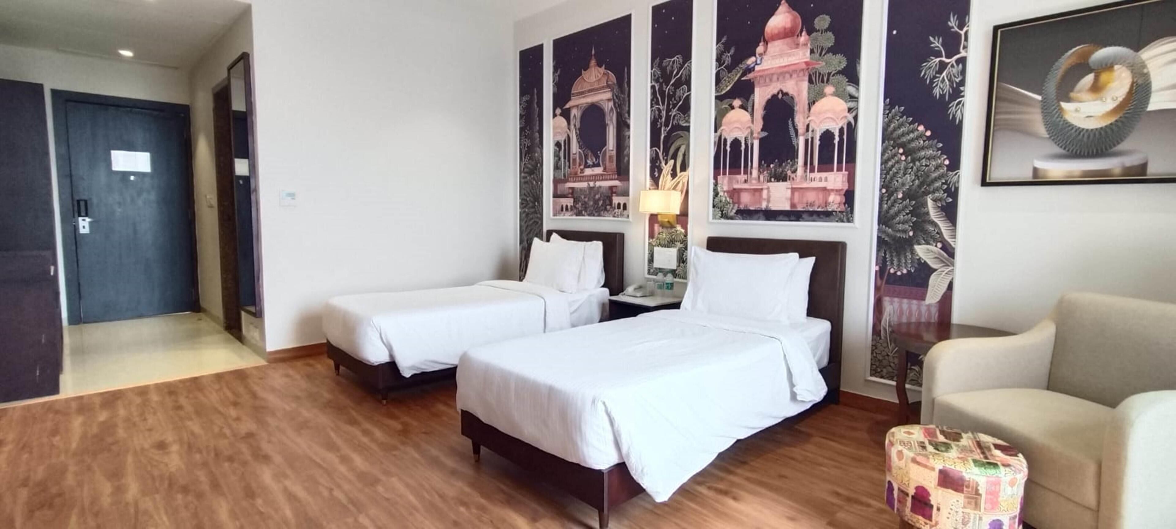 A hotel room with two beds, a chair, and a small table.