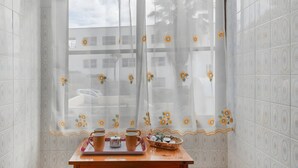 Eine Ecke des Raumes mit einem Fenster, einem Tisch mit Tablett und einem Stuhl.