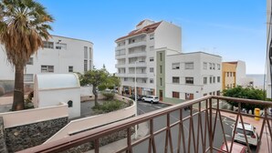 Ein Wohngebäude mit einer geschwungenen Fassade, Balkonen und einer Palme.