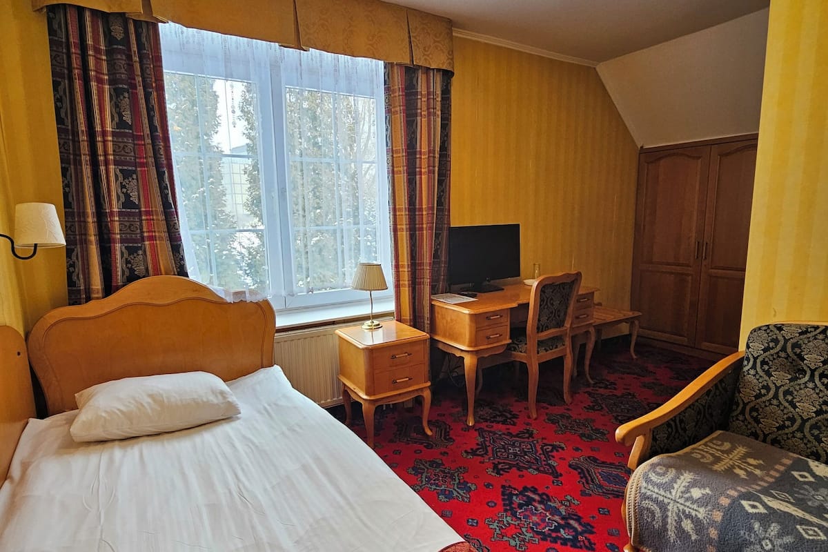 A hotel room with a bed, a desk with a chair, a television, and a wardrobe.