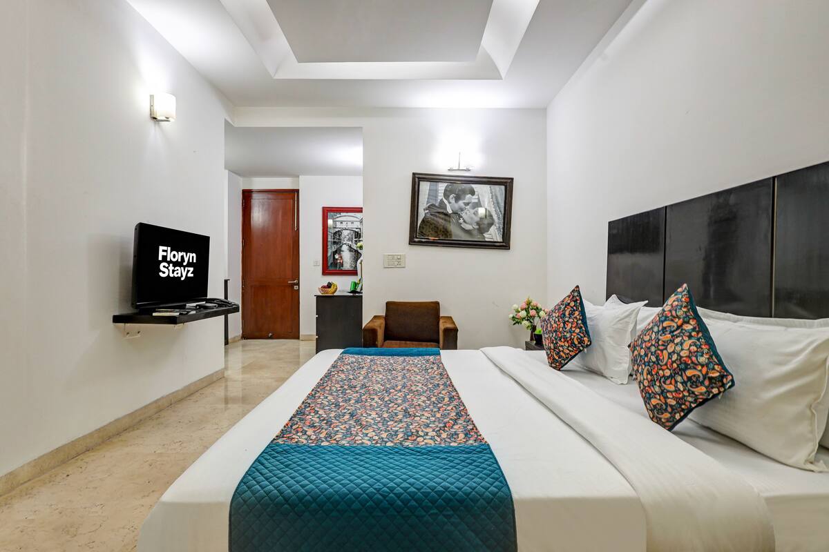 Une chambre d’hôtel comprenant un lit, une télévision, un bureau et une porte donnant sur une autre pièce.