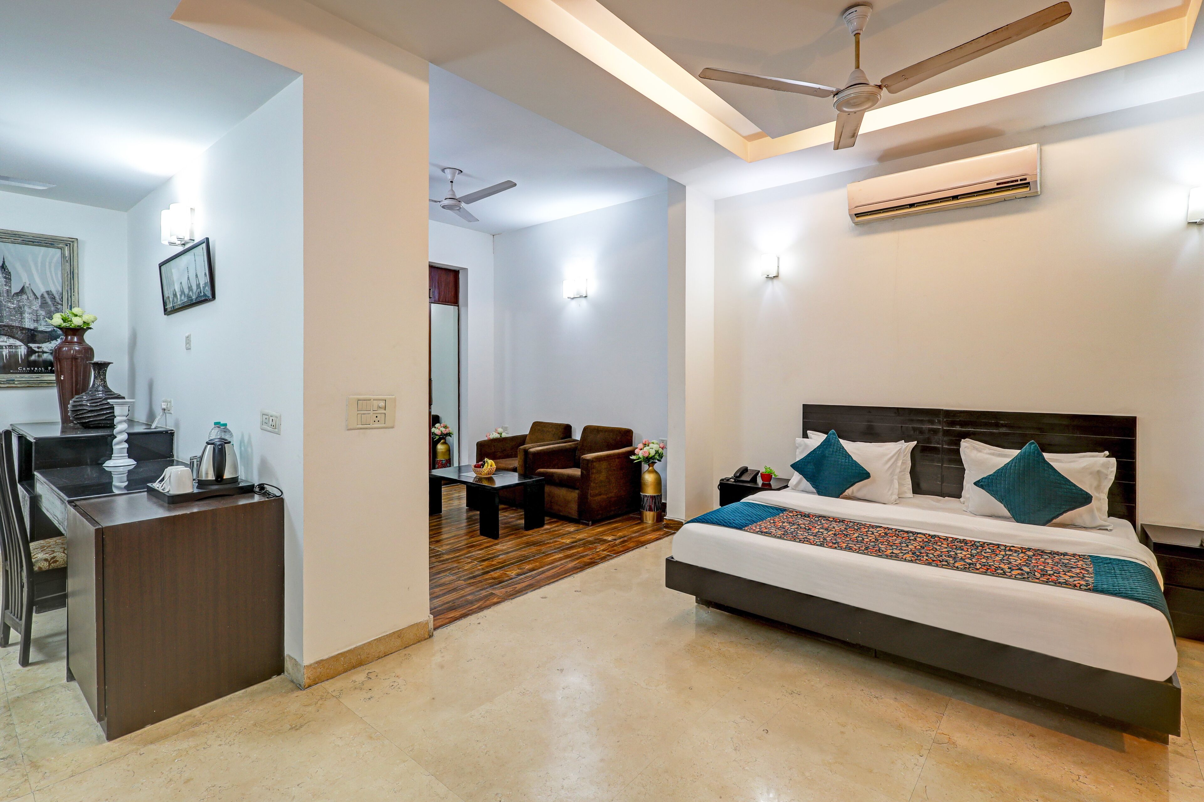 Una habitación de hotel con cama, escritorio, silla, ventilador de techo y aire acondicionado.