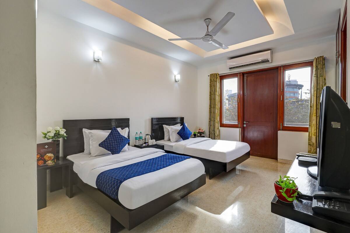 Une chambre d’hôtel avec deux lits, un bureau avec un ordinateur, un ventilateur de plafond et un appareil de climatisation.