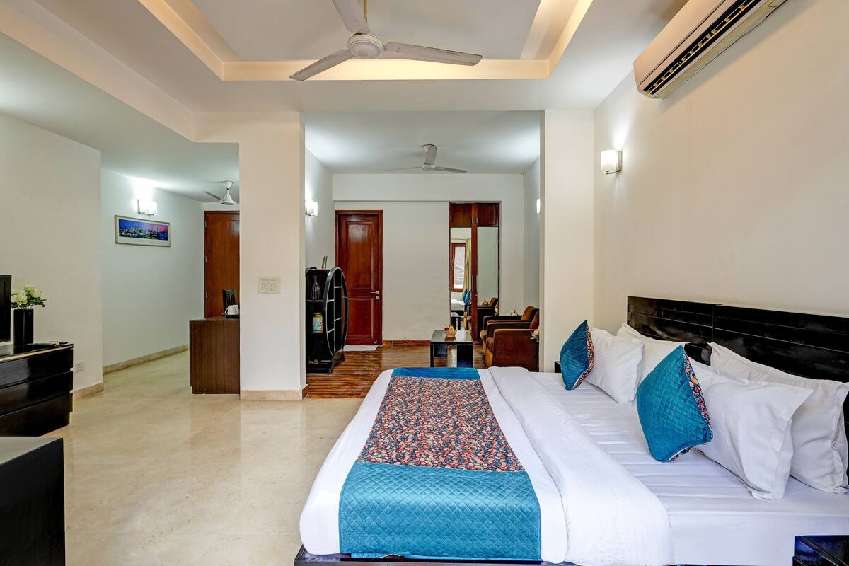 Une chambre d’hôtel équipée d’un lit, d’un bureau, d’une chaise, d’une armoire et d’un ventilateur de plafond.