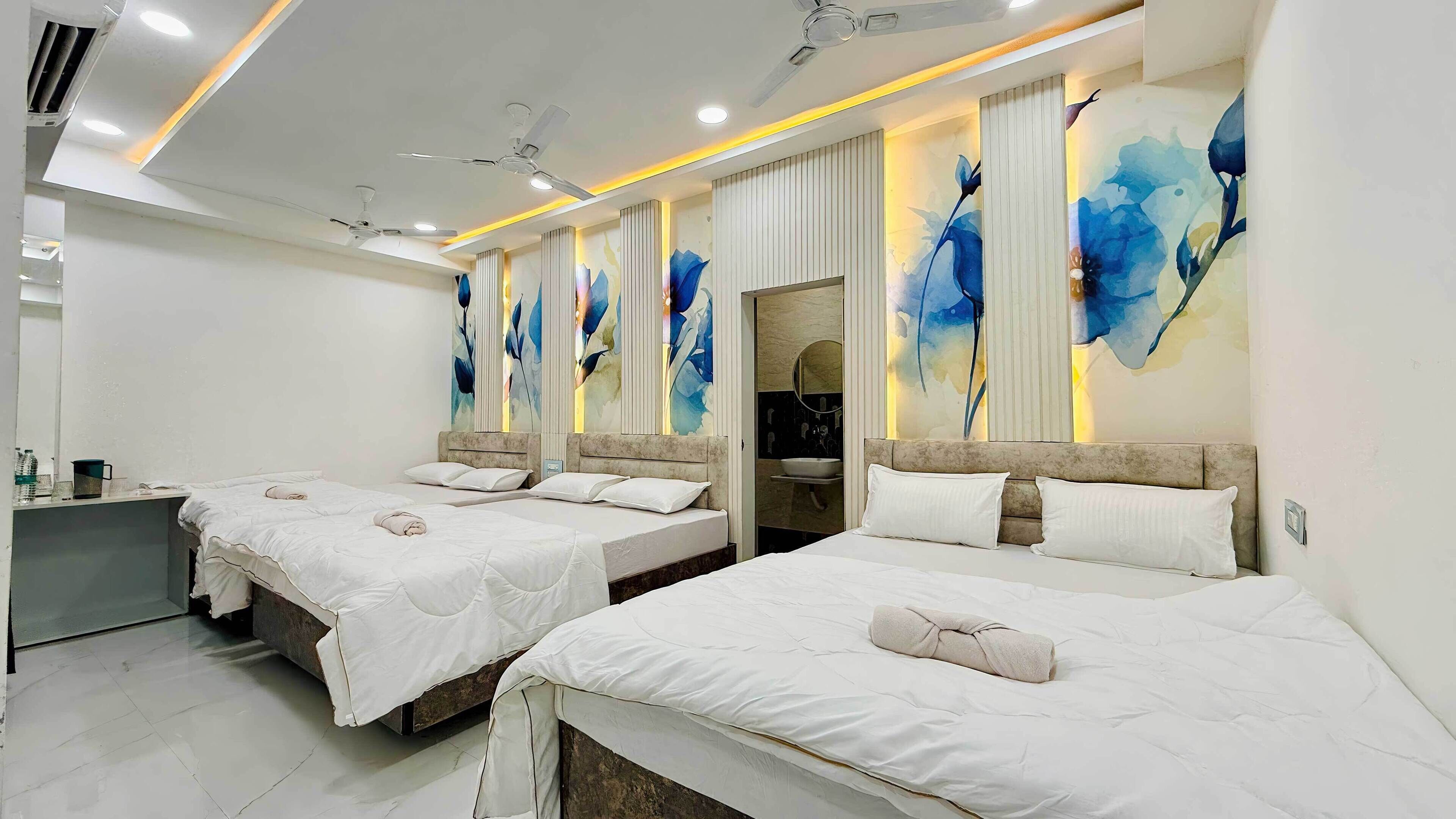 A hotel room with two beds, a bathroom, and a small desk.