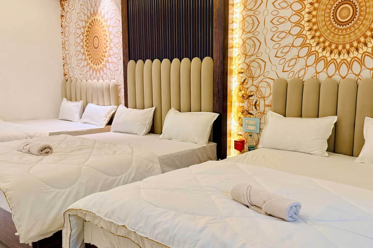 Ett hotellrum med två sängar, båda med vita sängkläder och kuddar, en sänggavel med vertikala ribbor och en dekorativ väggpanel med ett cirkelformat mönster.