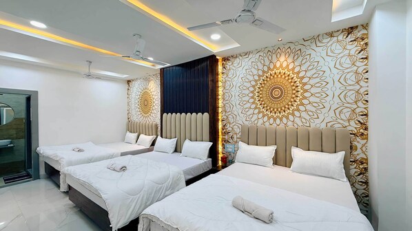 A hotel room with two beds, a bathroom, and a ceiling fan. - Hotel Om Mangalam Palace (Khandwa)