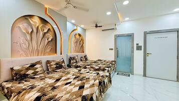 Habitación de hotel con diseño moderno, que incluye una cama grande con cubrecama estampado, una pared con paneles decorativos, un ventilador de techo y una puerta con cerradura de seguridad.