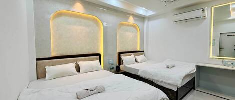 A hotel room with two beds, a desk, a mirror, and an air conditioning unit.