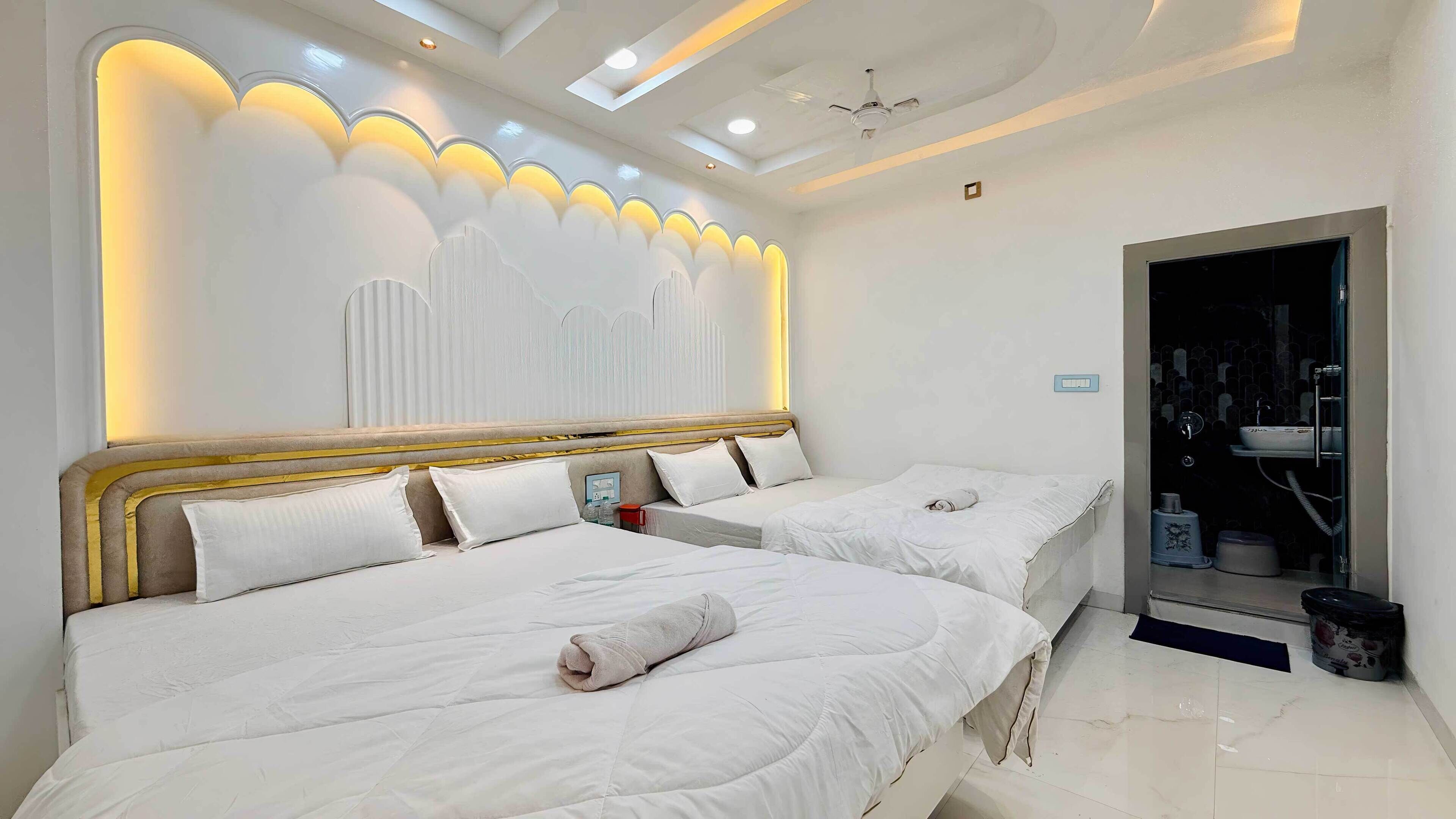 A hotel room with two beds, a modern ceiling design, and a bathroom visible through an open door.