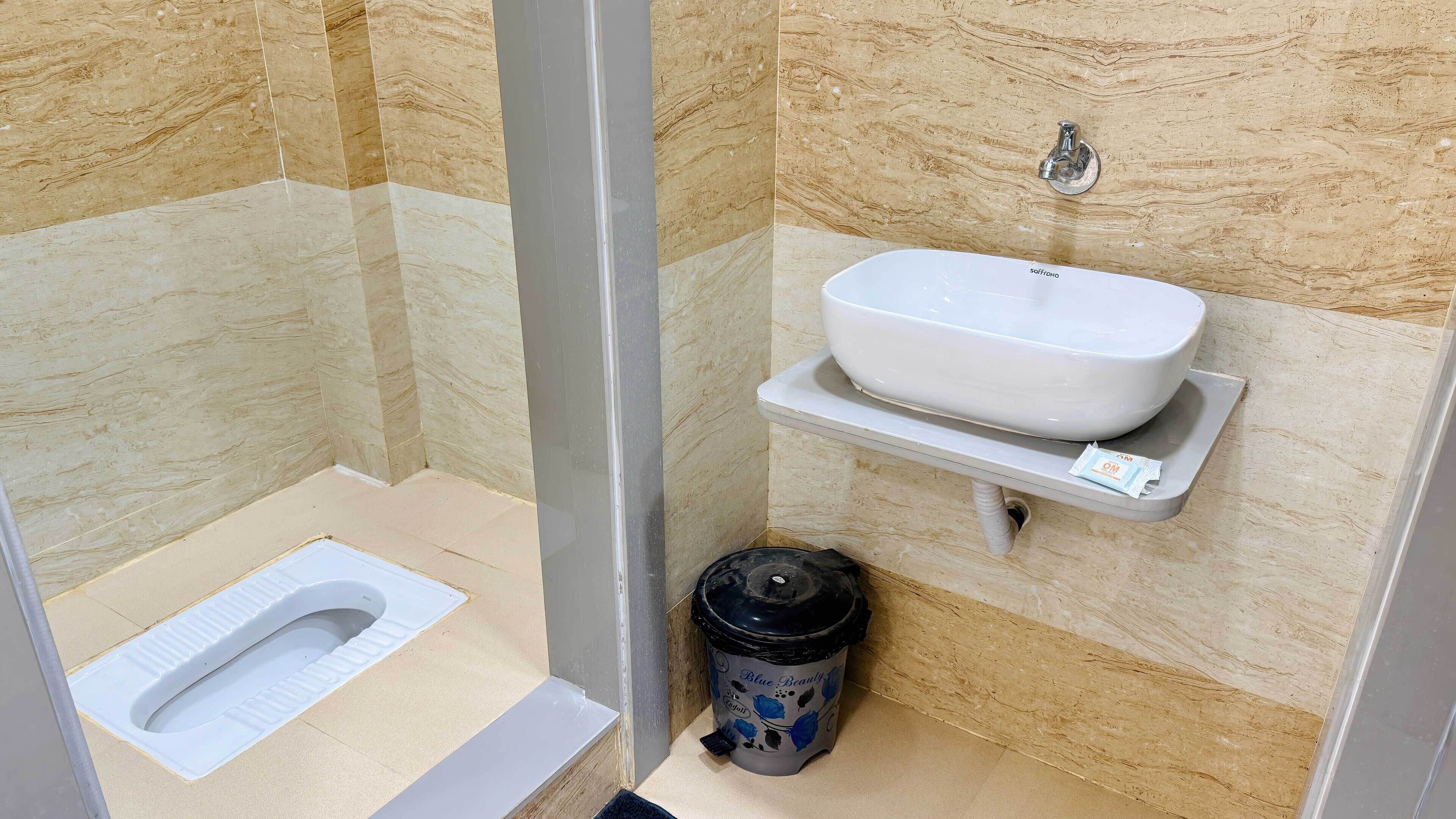 A small, compact bathroom with a toilet, a sink, and a trash bin.