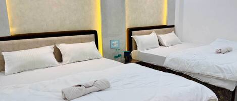 Two single beds with white linens, a nightstand with a water bottle and a thermos, and a wall socket.