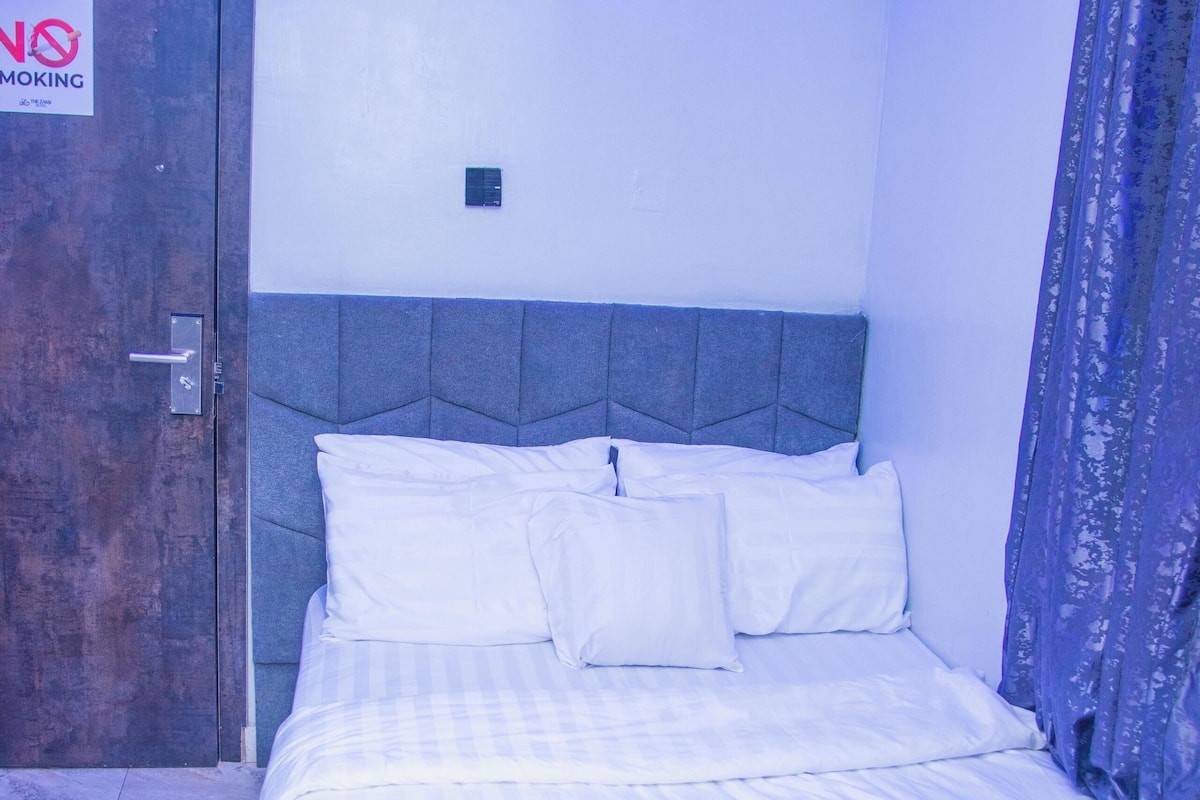 A bedroom with a bed, a door, and a 'No Smoking' sign.