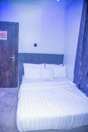 Un dormitorio con cama, una puerta y un cartel de 'No Smoking'.