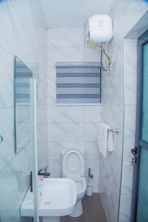 Un baño pequeño con inodoro, lavamanos y un secamanos fijado a la pared.