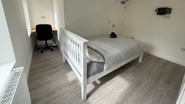 Ein Schlafzimmer mit einem Einzelbett, einem Schreibtisch und einem Stuhl.