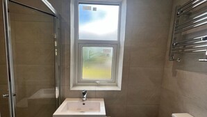 Ein Badezimmer mit Fenster, Waschbecken, Toilette und Dusche.
