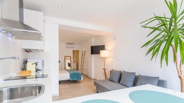 A modern kitchen with a stainless steel sink, a built-in stove, and a microwave. There is a dining area with a white table and chairs. A large potted plant is visible in the foreground. - 1 beach line. Malabau N2 (Tarifa)