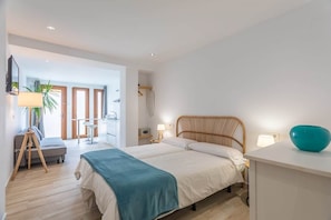 A modern bedroom with a bed, bedside tables, a desk, and a chair.