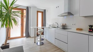 A modern kitchen with white cabinets, a stainless steel range hood, a sink, and a bar stool. - 1 beach line. Malabau N4 (Tarifa)