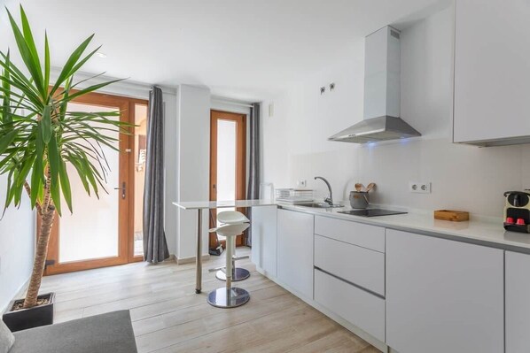 A modern kitchen with white cabinets, a stainless steel range hood, a sink, and a bar stool. - 1 beach line. Malabau N4 (Tarifa)