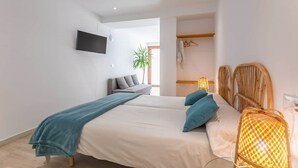 A modern bedroom with a bed, a TV mounted on the wall, a plant, and a wardrobe. - 1 beach line. Malabau N6 (Tarifa)
