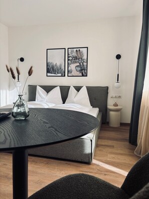 Ein modernes Schlafzimmer mit einem Bett, einem Nachttisch und einem runden Tisch mit einer Vase.