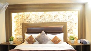Una cama bien hecha con un cabecero marrón, dos mesitas de noche con lámparas y papel tapiz con estampado floral.