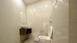 Un baño moderno con inodoro blanco, lavabo y espejo.
