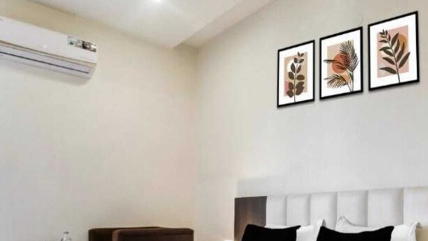 Una habitación de hotel moderna con una cama grande, una mesita de noche y un aire acondicionado instalado en la pared.