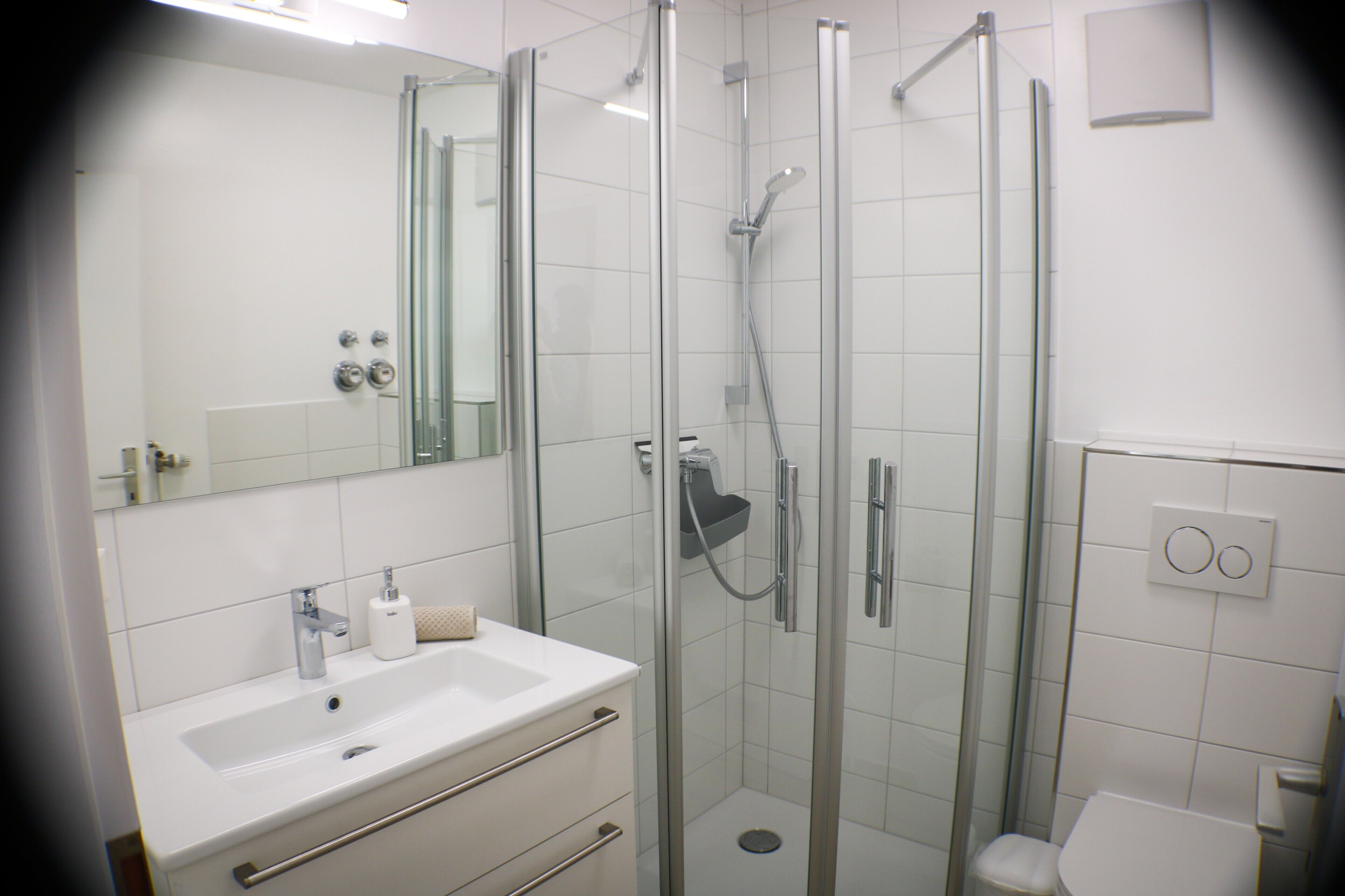 Un bagno moderno con doccia vetrata, lavandino bianco e servizi igienici.