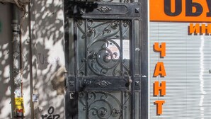 A metal gate with intricate designs, a closed shop with a sign in Cyrillic script, and a utility box on the wall. - Stylish apartment with Balkony in the center of Sofia ,metro,
WIFI, Smart TV ,AC (Sofia)