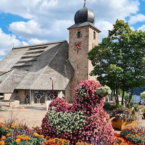 A building with a clock tower, a stone facade, and a large flower arrangement.