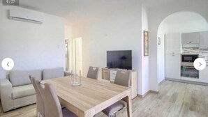 A modern living room with a wooden dining table, light-colored sofa, and a TV. - House Cà Luci 100 mt from the sea (Patù)