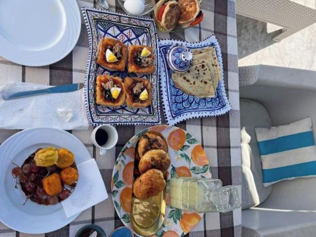 A table set with various dishes, including pastries and a bottle of drink, on a checkered tablecloth.
