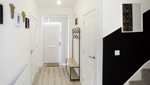 A hallway with a white door at the end, a bench, and a coat rack with hooks. - Charming 3-bedroom House in Balsall Heath, Birmingham (Birmingham)